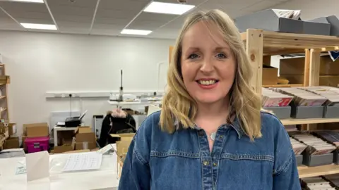 Anwen Roberts in an office, smiling at the camera