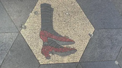 Close-up of ruby slippers which were inlaid into a gold paving stone on Eberle Street.