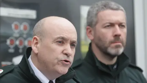 Pacemaker A head and shoulders image of Assistant Chief Constable Ryan Henderson and District Commander Superintendent Brendan Green. They are stood in front of Lurgan police station. Green is blurred in the background. In the foreground is Henderson, who is an older, bald man. He is mid-speech.