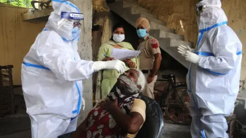 Getty Images Health workers in PPE coveralls take swab samples from residents of Patiala.