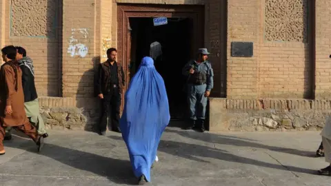 AFP A woman walks into a building in Herat