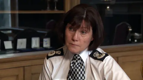 Police Scotland Chief Constable Jo Farrell sits astatine  a desk