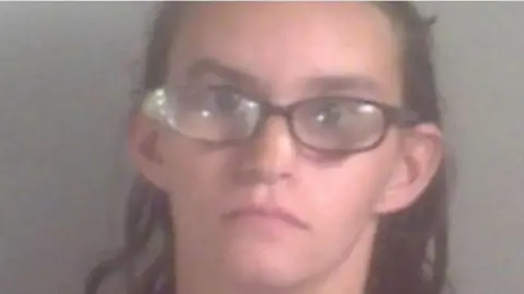 Kent Police Jody Simpson in a police mugshot in which she is looking at the camera. She is wearing glasses and has long brown hair.