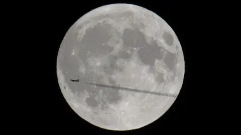 Woody's Elf Supermoon captured with a plane flying in front of it