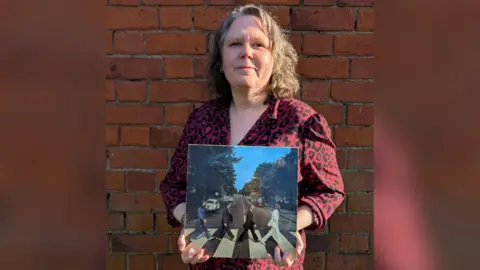 Emma Bowden holding a copy of Abbey Road by The Beatles on vinyl.