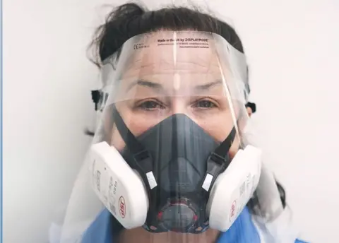 We Care Together Jodie Bond, a community nurse in unplanned care at Norfolk Community Health and Care NHS Trust, wearing a face shield and respirator