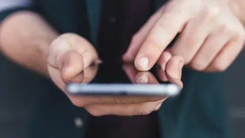 Getty Images Man holding a mobile phone