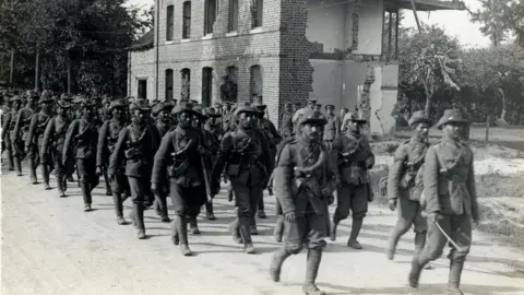 H. D. Girdwood via Wikimedia Commons Garhwali riflemen marching past a ruined building somewhere in France, 1915