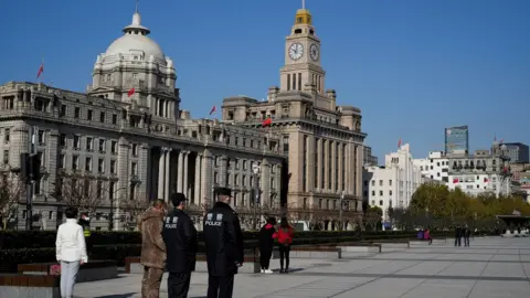 Reuters Pedestrians and police guards stand to attention for a three-minute silence in Shanghai