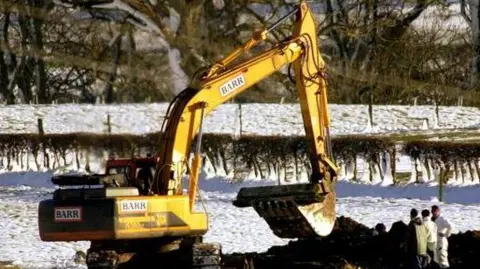 Generic shot of yellow mechanical digger in action on snow covered land