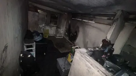 Tiffany Burned kitchen area, all the walls are black with smoke damage and the fixtures appear unusable.