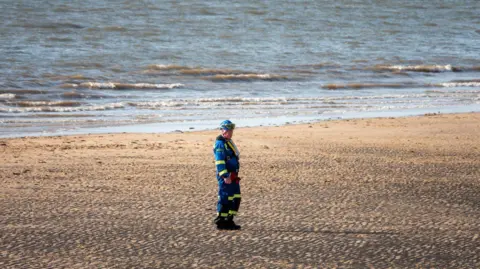 HM Coastguard Fleetwood Rescuer on beach wears reflective clothing