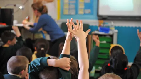 BBC Children raise their hands in school class