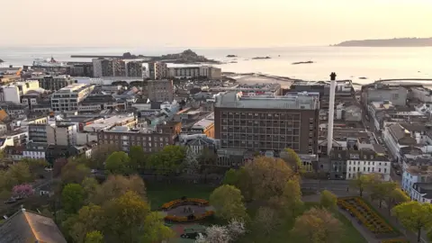 BBC A picture of Jersey General Hospital taken from above. There is a number of buildings and trees surrounding it.
