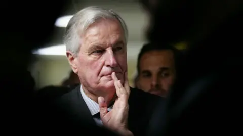 Getty Images A headshot of Michel Barnier holding his hand to his mouth looking pensive