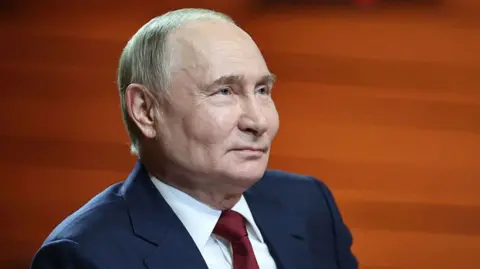 Close-up photo of Putin looking up, with an orange background. He's wearing a navy blue suit jacket and dark red tie