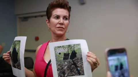 Getty Images Palm Beach County Sheriff PIO Teri Barber holds photographs of the firearm  and different   items recovered  adjacent   wherever  a fishy  was discovered during a property   league  regarding an evident  assassination effort  of erstwhile  President Donald Trump connected  September 15, 2024, successful  West Palm Beach, Florida.