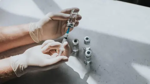 A medical professional holds a vaccine in hand