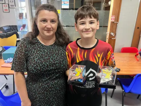 Mum in a leopard print dress with her son smiling at the camera.