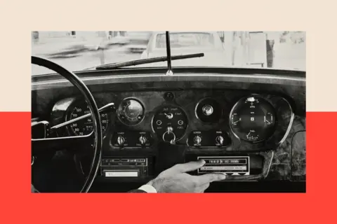 Condé Nast via Getty Images A male driver wearing sunglasses as seen through the rearview mirror, as he operates an old car stereo system 