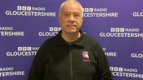 Nick Gazzard stood in front of BBC Gloucestershire's purple screen.
