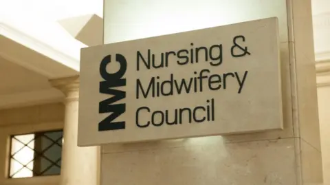 NMC Handout Interior of building with beige-coloured walls and a small window to the left. There is a sign with black lettering on a beige background which says "NMC Nursing and Midwifery Council".