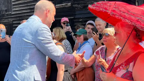 Sara Smith / BBC Prince William shakes hands with people from the community