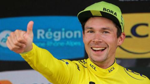Primoz Roglic celebrates on the podium after winning stage seven of the 2024 Criterium du Dauphine