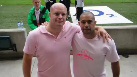 Supplied Nick and a friend. Nick is wearing a pink polo shirt. His friend is wearing a pink T-shirt