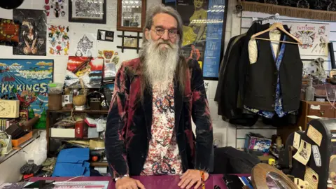BBC Rob Davies standing in his shop in front of several items