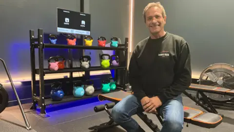 George Torr/BBC Terry Mohr sat on a gym bench in front of some kettle bells