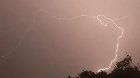 A dramatic bolt of lightning flashing across the night sky in Brentwood.