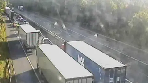 Highways England Lorries and cars bumper to bumper on the M11 in Essex in one direction. On the other, some cars are travelling.