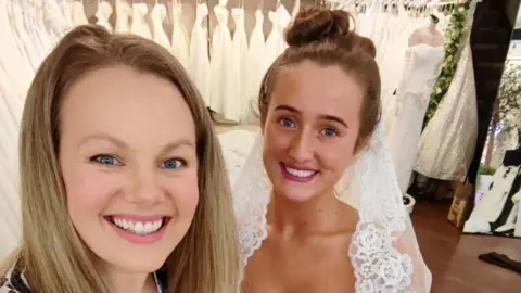 Sew In Love Emily Grant has long blonde hair and wears a zebra top while Venezuela Fury is in her wedding dress