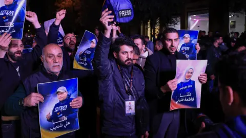Reuters A man raises a press helmet as people take part in a demonstration following the killing of Lebanese journalists, Al Manar reporter Ali Shaib, Al Mayadeen reporter Fatima Ftouni and cameraman Mohammed Ftouni 