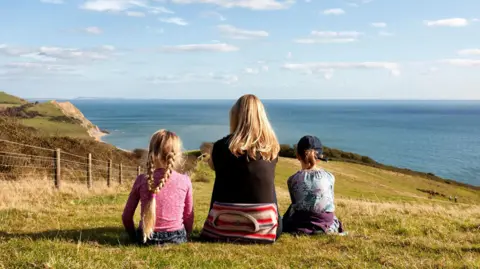 A mother and her two daughters view the Jurassic Coast, Dorset.