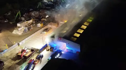 Dan Jessup Smokes pours out the windows and doors of a warehouse at night. 