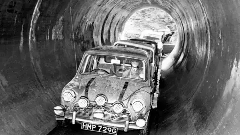 Getty Images Shot from The Italian Job, showing minis driving through large sewer pipes in coventry