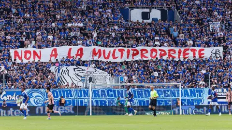 Strasbourg's ultras hold up a banner in protest at the club being part of a multi-club ownership structure