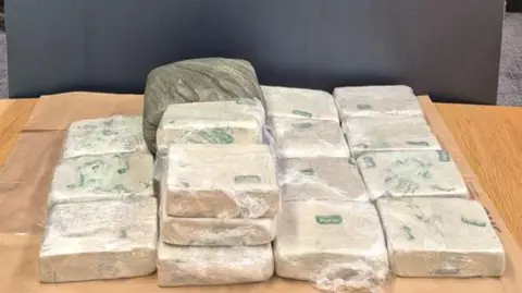 An Garda Síochána More than a dozen large square bricks of white heroin, wrapped in clear plastic, arranged on a wooden table