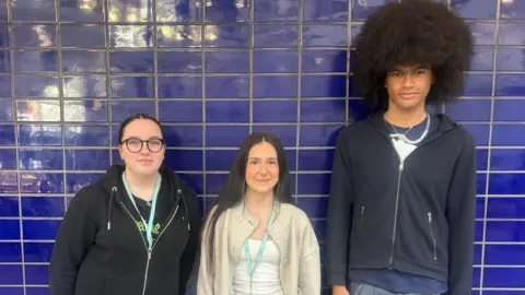 Esme Neal, Gabby Congiu and Dre Frazer stood in front of a wall with dark blue tiles