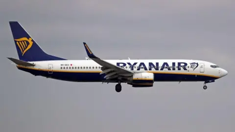 Getty Images A Ryanair plane in the air with white, blue and gold livery