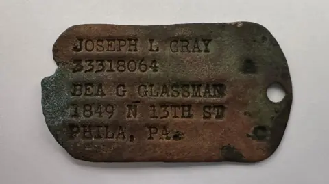 Ivor Ramsden A rusted worn dog tag, reading Joseph L Gray, 33318064, Bea G Glassman, 1849 N 13th St. Phila, PA.
