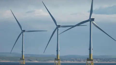 Getty Images Three offshore wind turbines in the sea off the coast of the UK