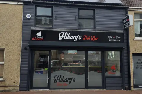 Leanne Jones A two-storey building with black cladding and a sign saying 'award winner', 'Hikary's Fish Bar' and 'Fish and Chip Takeaway'