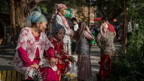 Getty Images Uyghur women wearing traditional clothes seen watching the Uyghur dancing show in the streets of Kashgar, northwestern Xinjiang.
