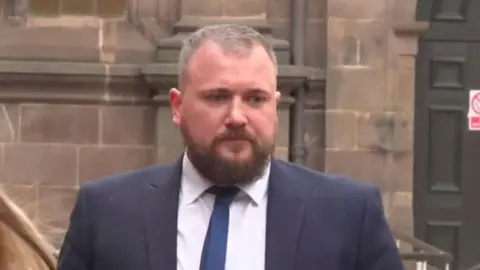Steven Allcock leaving court. He's wearing a white shirt and tie.