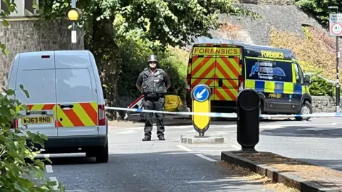 An armed police man near two patrol cars on Clifton Suspension Bridge