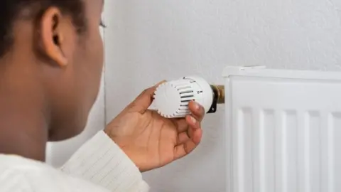 Getty Images Woman adjusting a radiator