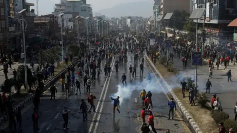 Reuters A demonstrator throws a tear gas cylinder back at police in Kathmandu